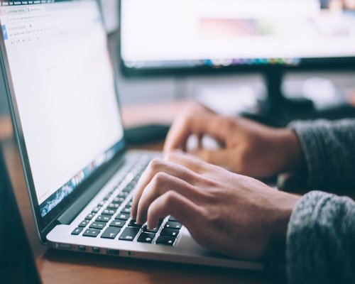 A close up view of an individual typing an email on a laptop