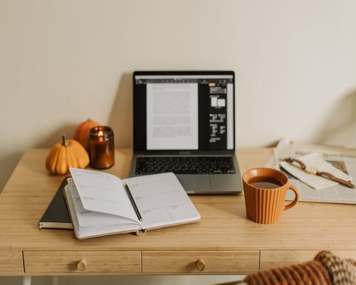 A notebook planner and a cup of tea on a comfortable home desk